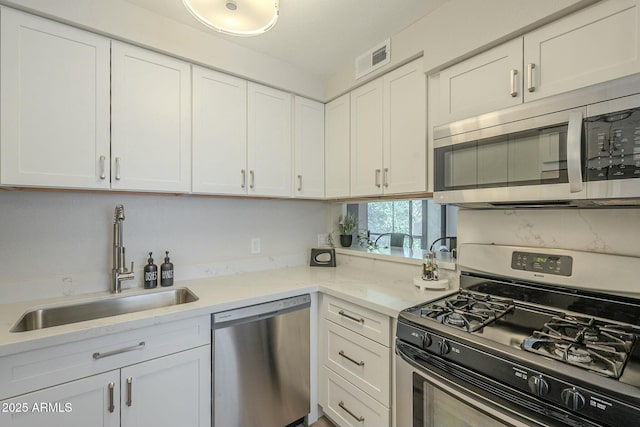 kitchen featuring a sink, visible vents, white cabinetry, appliances with stainless steel finishes, and light stone countertops