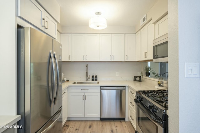 kitchen with white cabinets, appliances with stainless steel finishes, light countertops, and a sink