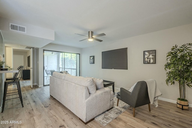 living area featuring ceiling fan, light wood-style flooring, visible vents, and baseboards