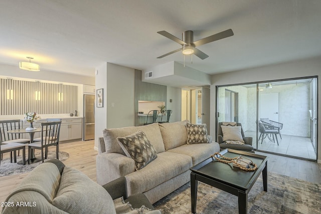 living area with visible vents, light wood-style flooring, and a ceiling fan