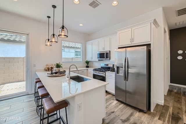 kitchen with stainless steel appliances, visible vents, a kitchen breakfast bar, white cabinets, and light countertops