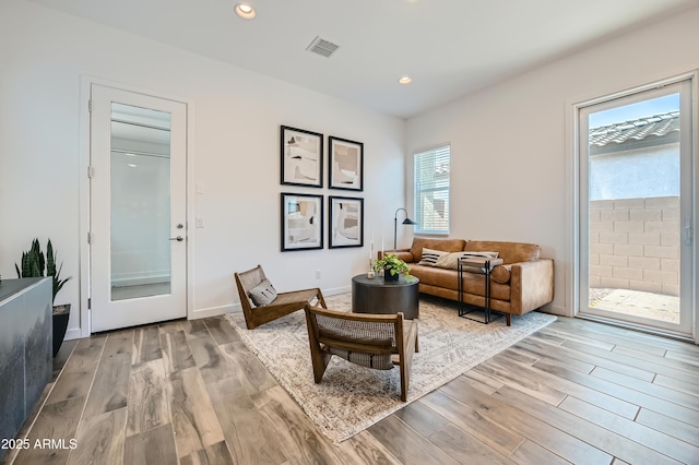 living room featuring light wood-style flooring, visible vents, baseboards, and recessed lighting