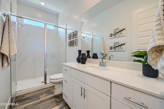 bathroom featuring toilet, a marble finish shower, wood finished floors, and vanity