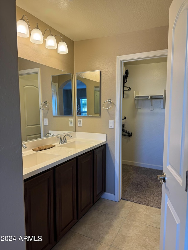 bathroom with a sink, a spacious closet, double vanity, and tile patterned floors