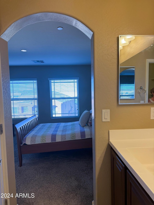 bedroom with arched walkways, visible vents, and carpet flooring