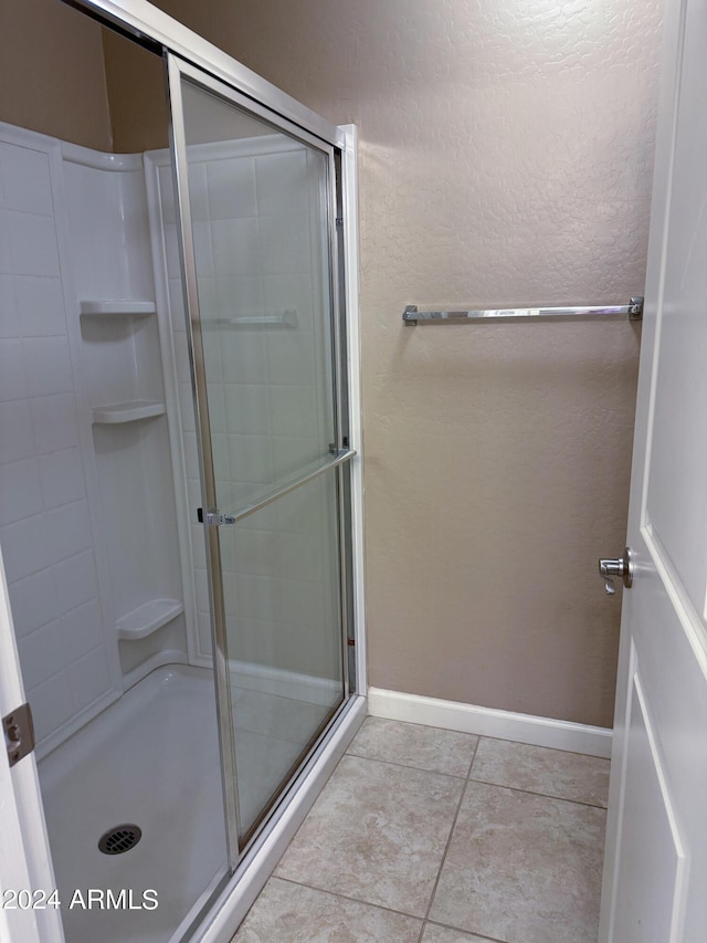 bathroom featuring tile patterned floors, a shower stall, and baseboards