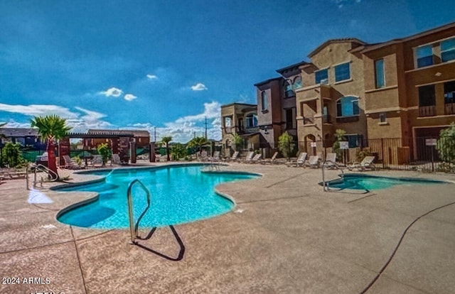 community pool with a patio area, a pergola, and fence