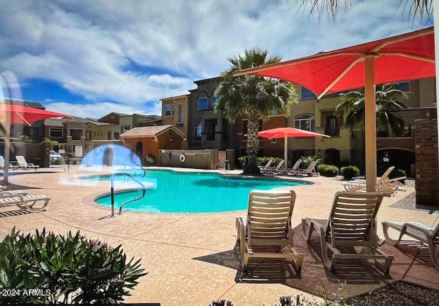 community pool featuring a patio area, a residential view, and fence