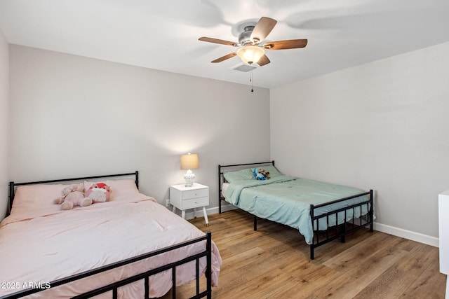 bedroom with light wood finished floors, a ceiling fan, visible vents, and baseboards