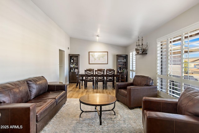 living area with light wood-style floors and vaulted ceiling