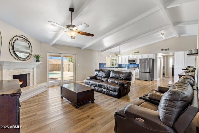 living room featuring light wood-type flooring, baseboards, a fireplace, and visible vents