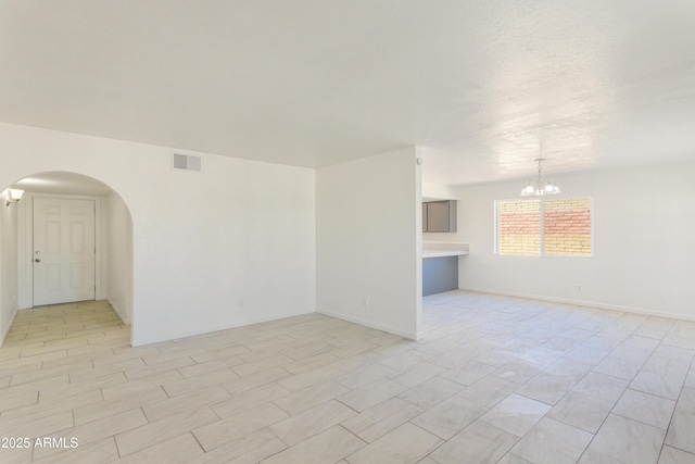 unfurnished room with a notable chandelier