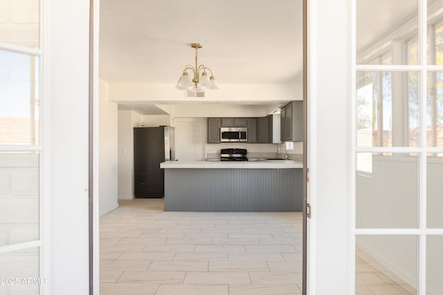 kitchen with sink, appliances with stainless steel finishes, gray cabinets, kitchen peninsula, and a notable chandelier