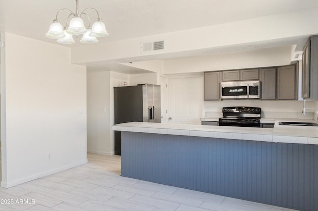 kitchen featuring pendant lighting, sink, kitchen peninsula, and appliances with stainless steel finishes