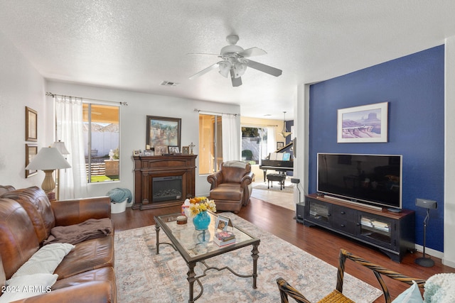 living room featuring ceiling fan, a textured ceiling, and dark hardwood / wood-style floors