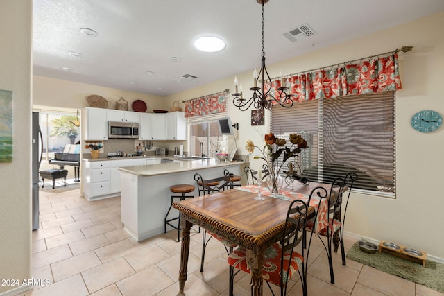 dining space featuring a notable chandelier, a healthy amount of sunlight, sink, and light tile patterned flooring