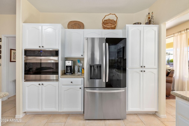 kitchen with white cabinets, light stone counters, stainless steel appliances, and light tile patterned floors