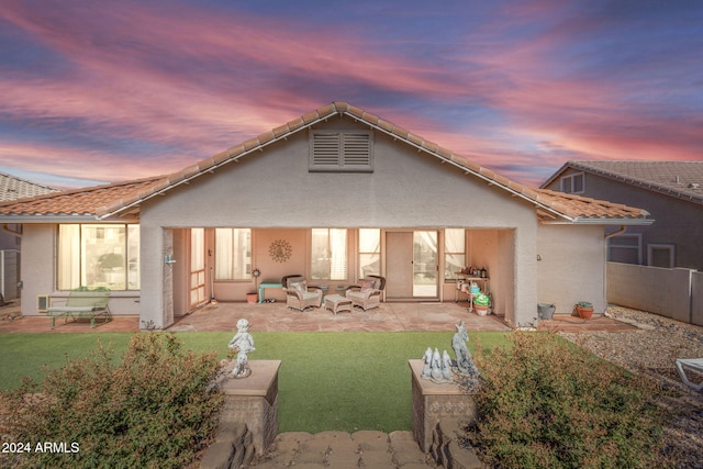 back house at dusk featuring a patio and a yard