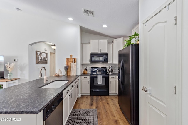 kitchen with sink, black appliances, kitchen peninsula, and white cabinets