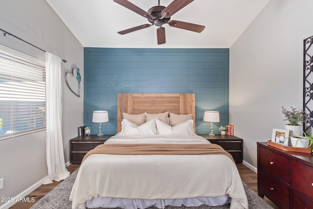 bedroom with dark wood-type flooring, ceiling fan, and wooden walls