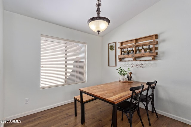 dining space featuring vaulted ceiling and dark hardwood / wood-style floors