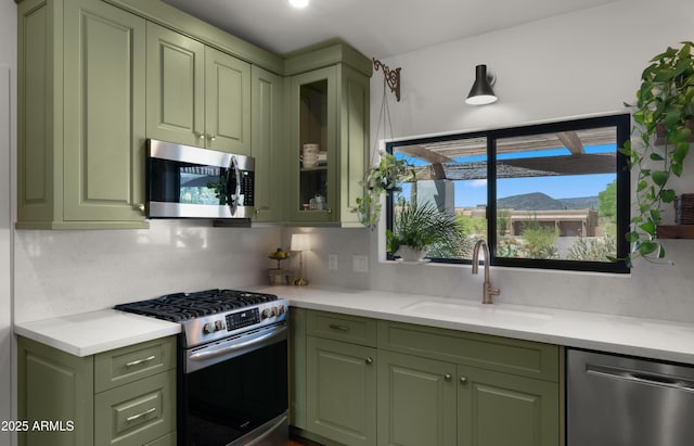 8049 E Serene St, Carefree, AZ 85377 - kitchen featuring green cabinetry, appliances with stainless steel finishes, light countertops, glass insert cabinets, and backsplash