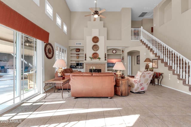 living room with light tile patterned floors, a towering ceiling, ceiling fan, and built in shelves