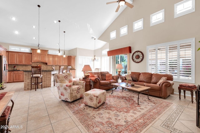 living room featuring high vaulted ceiling, light tile patterned flooring, and ceiling fan with notable chandelier