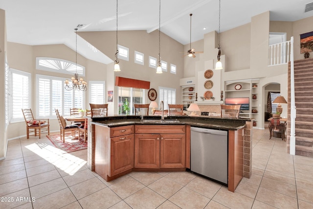 kitchen with built in shelves, dishwasher, sink, a kitchen island with sink, and ceiling fan with notable chandelier