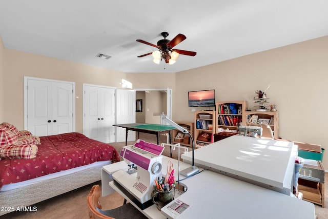 carpeted bedroom with ceiling fan and multiple closets