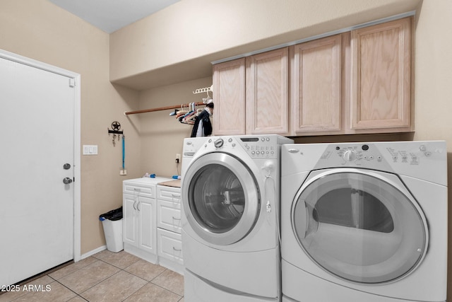 washroom featuring separate washer and dryer, light tile patterned floors, and cabinets