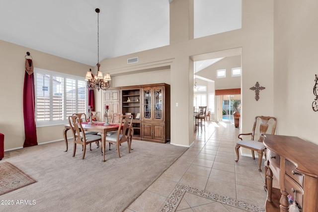 dining space with light tile patterned floors, high vaulted ceiling, and an inviting chandelier