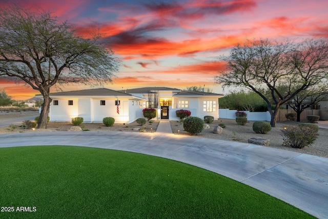 view of front of house with a fenced front yard, concrete driveway, and a front lawn