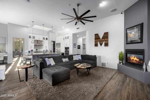 living area with a glass covered fireplace, visible vents, dark wood finished floors, and recessed lighting