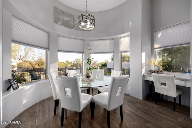 dining space featuring a notable chandelier, a high ceiling, and wood finished floors