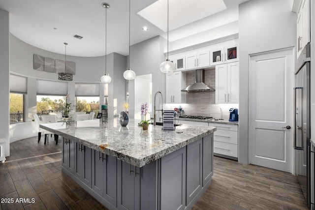 kitchen featuring dark wood-type flooring, visible vents, wall chimney exhaust hood, and tasteful backsplash