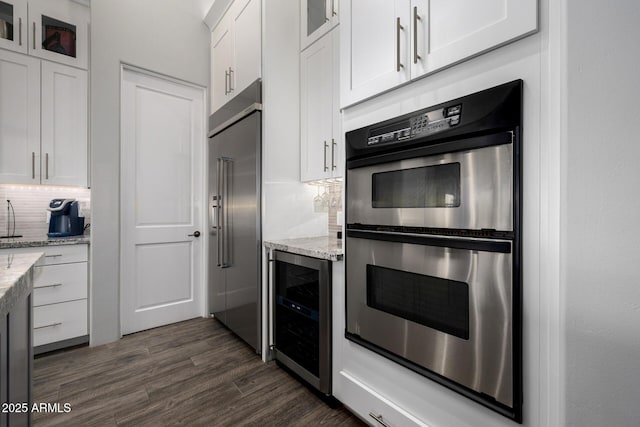 kitchen featuring wine cooler, dark wood-style flooring, stainless steel appliances, tasteful backsplash, and white cabinets