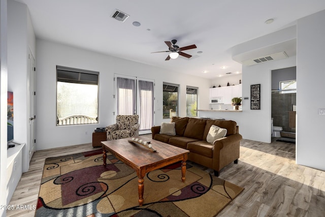 living room featuring a ceiling fan, visible vents, and light wood-style floors