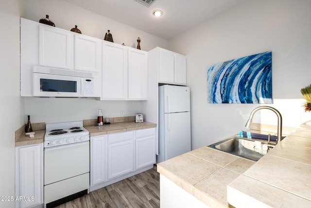 kitchen featuring white appliances, light countertops, light wood-style floors, white cabinetry, and a sink