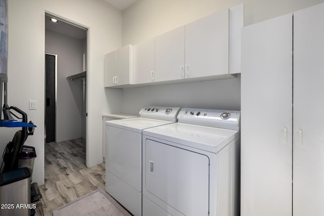 washroom featuring light wood-type flooring, independent washer and dryer, and cabinet space