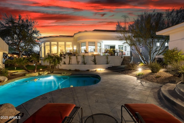 pool at dusk with stairs, an outdoor pool, and a patio