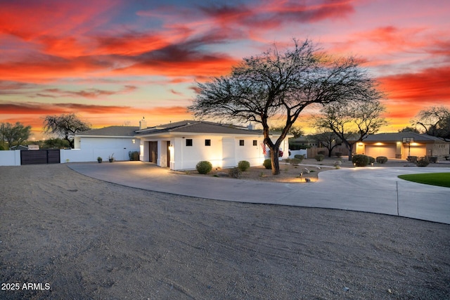 view of front of property featuring a gate, fence, and curved driveway