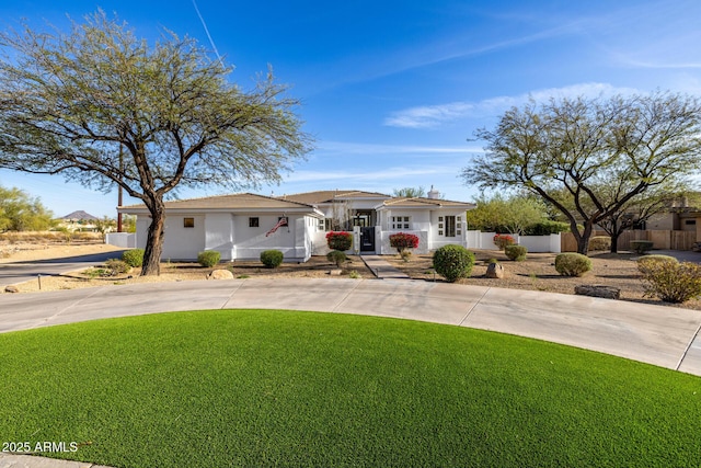 view of front of home with concrete driveway, a front lawn, and fence