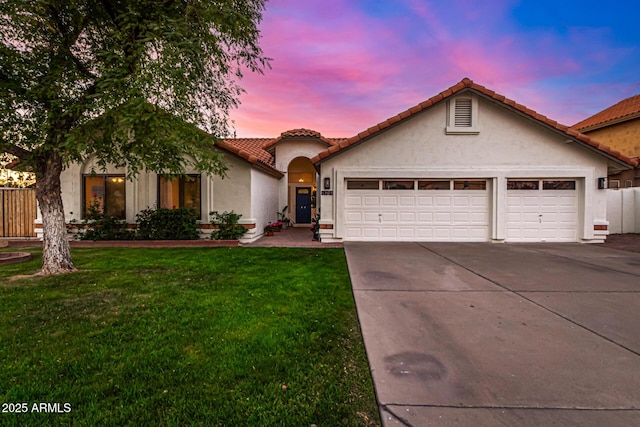 view of front of house with an attached garage, fence, driveway, stucco siding, and a front yard