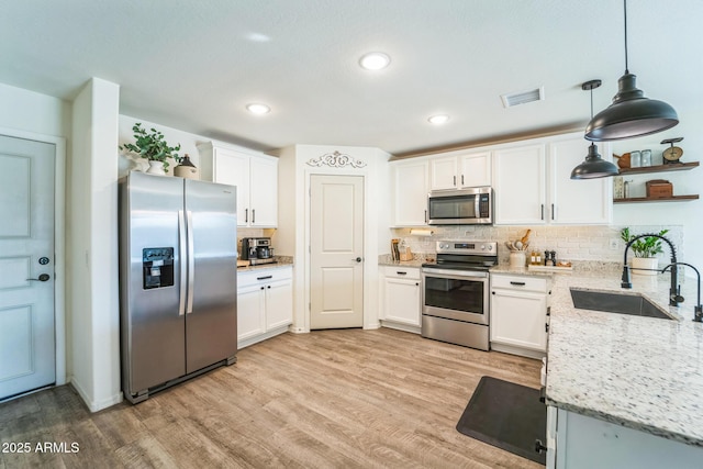 kitchen with appliances with stainless steel finishes, white cabinetry, hanging light fixtures, and sink