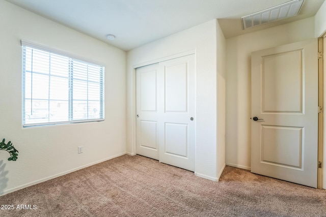 unfurnished bedroom with light colored carpet and a closet