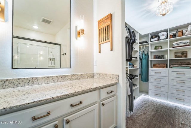 bathroom featuring a shower with shower door and vanity