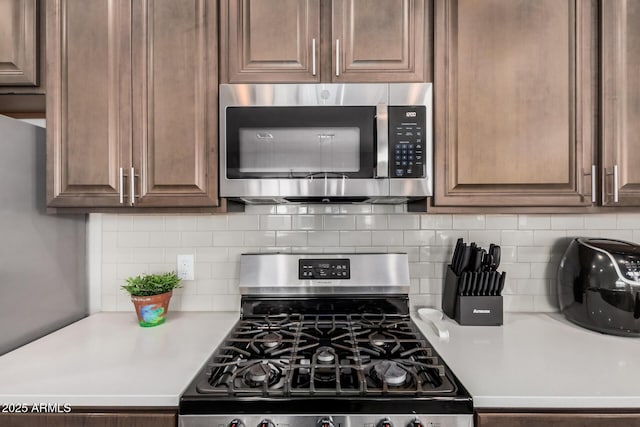kitchen featuring light countertops, decorative backsplash, and stainless steel appliances