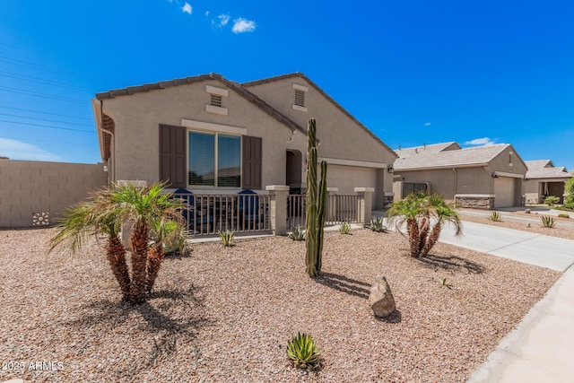 view of front of house with stucco siding, an attached garage, fence, and driveway