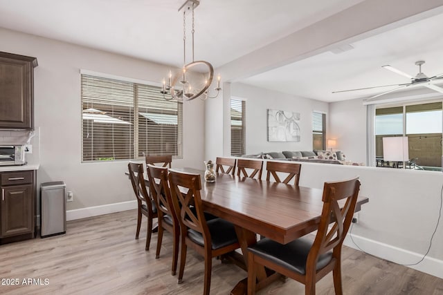 dining space with a toaster, light wood-style floors, baseboards, and ceiling fan with notable chandelier